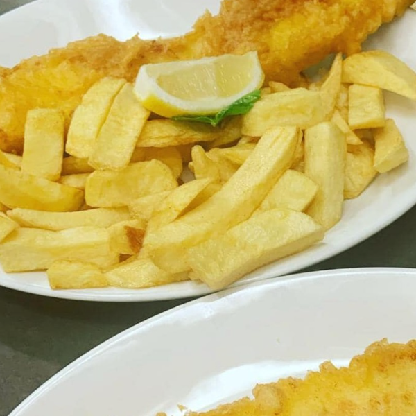 Fish and chips on a white place with a piece of lemon