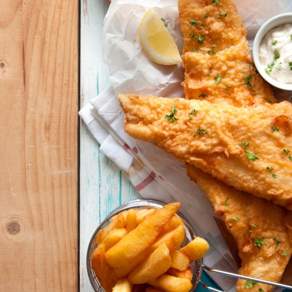 Fish and Chips on a wooden table with lemon and tartare sauce